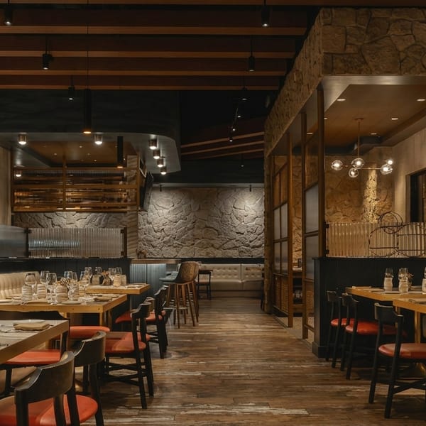 Elegant restaurant interior with set tables, banquette seating, stone walls, and warm lighting.